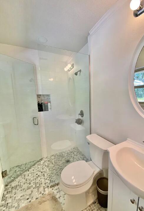 123 NW Sotir St, Fort Walton Beach, FL 32548 - bathroom with toilet, tile patterned floors, a shower stall, and a sink