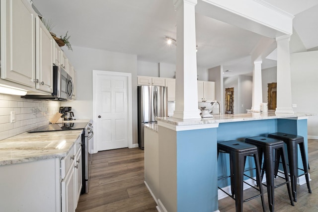 8512 Turnberry Ct Unit 8512, Miramar Beach, FL 32550 - kitchen featuring ornate columns, appliances with stainless steel finishes, a breakfast bar, and decorative backsplash
