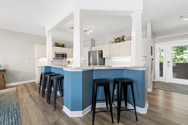 8512 Turnberry Ct Unit 8512, Miramar Beach, FL 32550 - kitchen featuring ornate columns, appliances with stainless steel finishes, tasteful backsplash, a kitchen bar, and wood finished floors