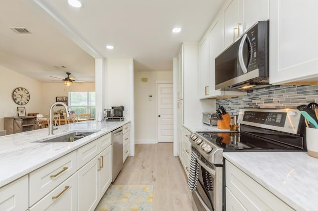 1148 Pin Oak Cir, Niceville, FL 32578 - kitchen featuring appliances with stainless steel finishes, a sink, white cabinets, tasteful backsplash, and light wood-type flooring
