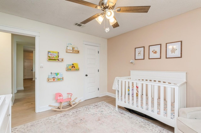 1148 Pin Oak Cir, Niceville, FL 32578 - bedroom featuring light wood finished floors, a crib, baseboards, and a ceiling fan