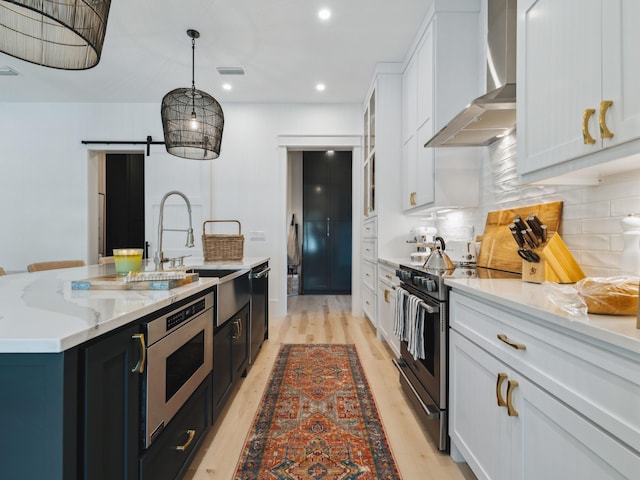 241 N 7th St, Santa Rosa Beach, FL 32459 - kitchen with wall chimney exhaust hood, appliances with stainless steel finishes, an island with sink, white cabinets, and a sink