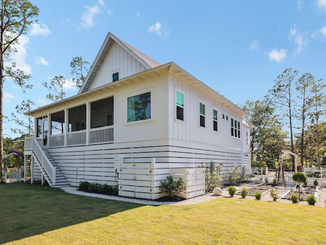 241 N 7th St, Santa Rosa Beach, FL 32459 - view of side of home with board and batten siding, a sunroom, a lawn, and stairway