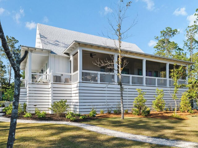 241 N 7th St, Santa Rosa Beach, FL 32459 - view of front of property featuring roof with shingles, board and batten siding, a sunroom, and a front yard