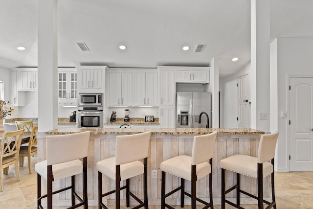 276 Sandy Cay Dr, Miramar Beach, FL 32550 - kitchen with appliances with stainless steel finishes, light stone countertops, white cabinetry, recessed lighting, and a kitchen breakfast bar