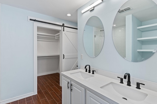 276 Sandy Cay Dr, Miramar Beach, FL 32550 - bathroom with double vanity, a walk in closet, wood finished floors, recessed lighting, and baseboards