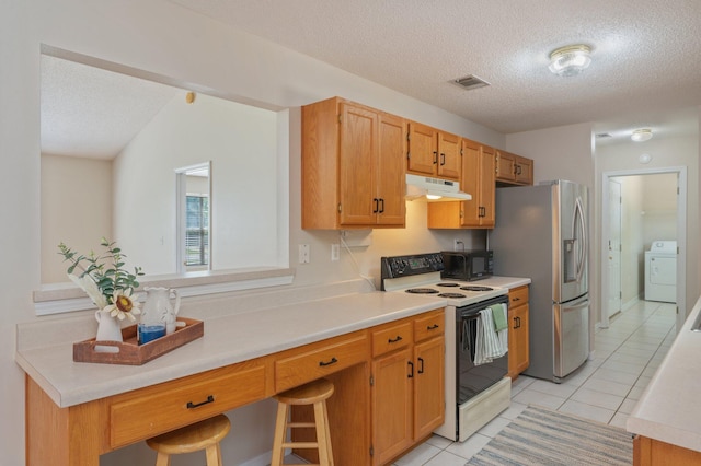 390 Brackin St, Crestview, FL 32539 - kitchen featuring white electric range oven, under cabinet range hood, a textured ceiling, washer / dryer, and light tile patterned flooring