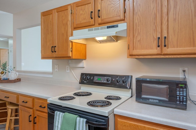 390 Brackin St, Crestview, FL 32539 - kitchen with range with electric stovetop, under cabinet range hood, black microwave, and light countertops
