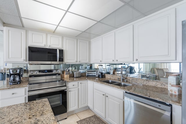 11483 Front Beach Rd Unit 202, Panama City Beach, FL 32407 - kitchen with stainless steel appliances, a sink, light tile patterned floors, white cabinets, and a paneled ceiling