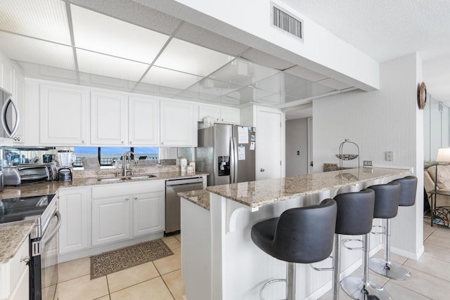11483 Front Beach Rd Unit 202, Panama City Beach, FL 32407 - kitchen featuring a sink, appliances with stainless steel finishes, light stone countertops, white cabinets, and a breakfast bar area