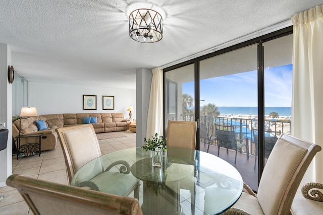 11483 Front Beach Rd Unit 202, Panama City Beach, FL 32407 - dining room featuring light tile patterned floors, a water view, a textured ceiling, and a wall of windows