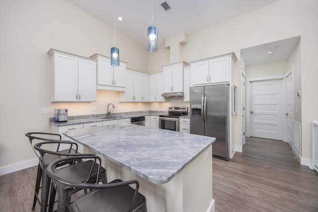 340 Bluefish Dr Unit 106, Fort Walton Beach, FL 32548 - kitchen with appliances with stainless steel finishes, a sink, baseboards, a kitchen breakfast bar, and under cabinet range hood