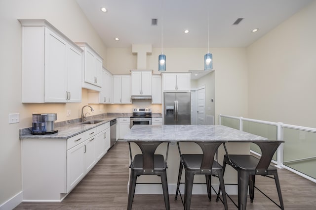 340 Bluefish Dr Unit 106, Fort Walton Beach, FL 32548 - kitchen with appliances with stainless steel finishes, a sink, a center island, white cabinetry, and a kitchen breakfast bar
