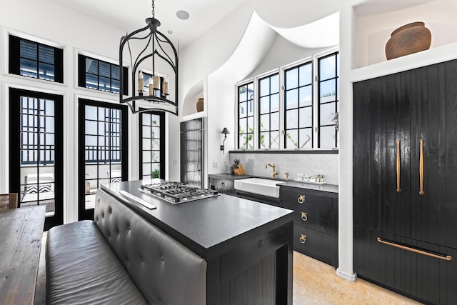 25 Moongate Ct, Inlet Beach, FL 32461 - kitchen with dark cabinetry, stainless steel gas cooktop, a sink, a towering ceiling, and hanging light fixtures