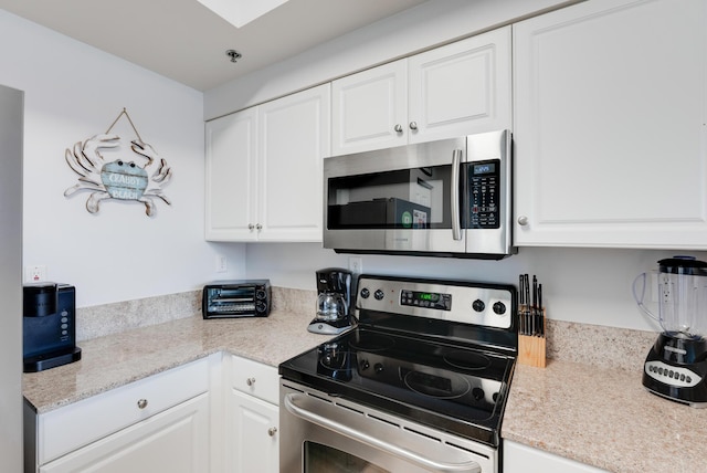 9900 S Thomas Dr Unit 2226, Panama City Beach, FL 32408 - kitchen featuring appliances with stainless steel finishes, white cabinets, and a skylight