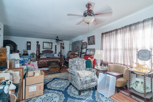 2522 Lake Silver Rd, Crestview, FL 32536 - living area with a textured ceiling, ceiling fan, wood finished floors, and a wood stove