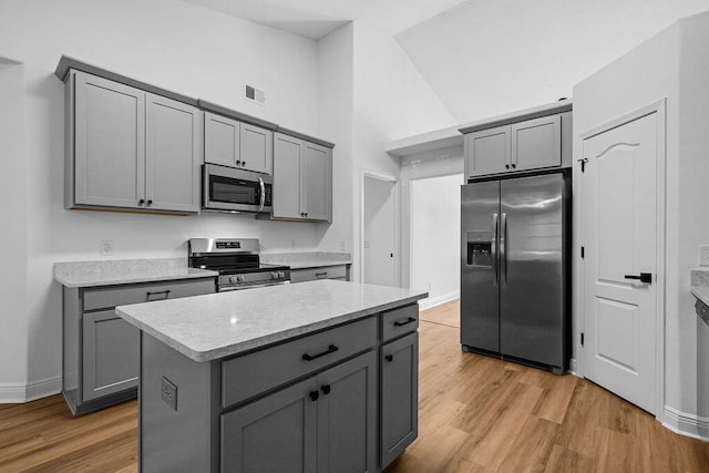 516 Vulpes Sanctuary Loop, Crestview, FL 32536 - kitchen featuring stainless steel appliances, gray cabinetry, light wood-type flooring, baseboards, and high vaulted ceiling