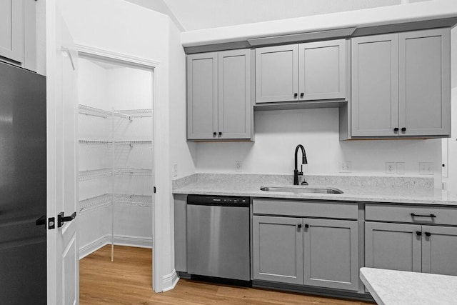 516 Vulpes Sanctuary Loop, Crestview, FL 32536 - kitchen with stainless steel dishwasher, a sink, gray cabinetry, light wood finished floors, and light stone countertops