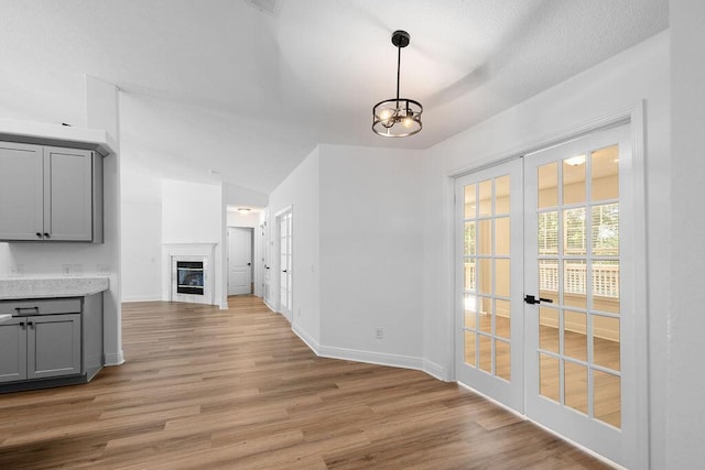 516 Vulpes Sanctuary Loop, Crestview, FL 32536 - unfurnished dining area featuring french doors, light wood-style flooring, a glass covered fireplace, and lofted ceiling