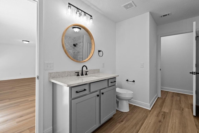 516 Vulpes Sanctuary Loop, Crestview, FL 32536 - bathroom with wood finished floors, vanity, toilet, a textured ceiling, and baseboards