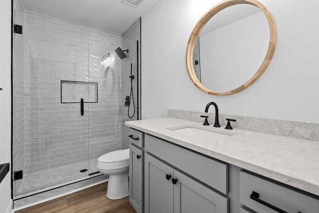 516 Vulpes Sanctuary Loop, Crestview, FL 32536 - bathroom featuring vanity, a stall shower, toilet, wood finished floors, and a textured ceiling