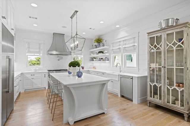 29 Tidal Bridge Way, Watersound, FL 32461 - kitchen featuring premium appliances, wall chimney exhaust hood, a sink, light wood-style floors, and a kitchen island