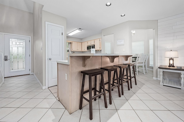 114 Mainsail Dr Unit C28, Miramar Beach, FL 32550 - kitchen featuring stainless steel microwave, light countertops, light tile patterned flooring, a kitchen breakfast bar, and baseboards