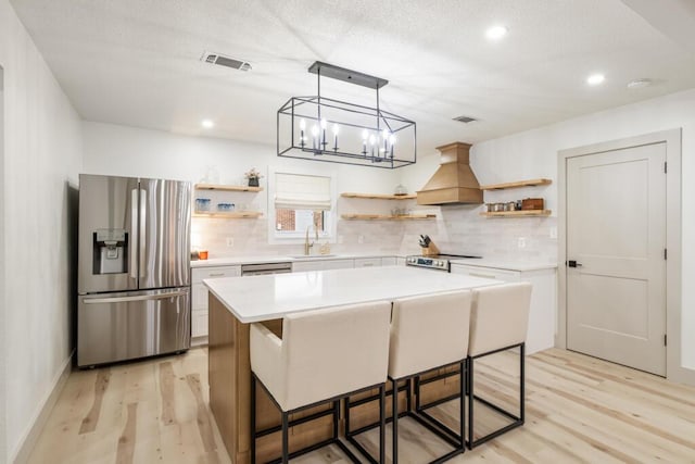 538 22nd St, Niceville, FL 32578 - kitchen featuring open shelves, stainless steel appliances, premium range hood, light wood finished floors, and a sink