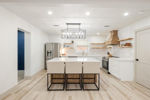 538 22nd St, Niceville, FL 32578 - kitchen featuring open shelves, appliances with stainless steel finishes, custom range hood, light wood-type flooring, and a kitchen island