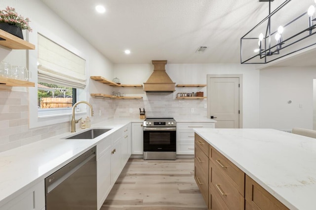 538 22nd St, Niceville, FL 32578 - kitchen with open shelves, stainless steel appliances, a sink, light wood-type flooring, and custom range hood