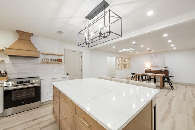 538 22nd St, Niceville, FL 32578 - kitchen with stainless steel electric range oven, custom range hood, light wood-type flooring, backsplash, and a kitchen island