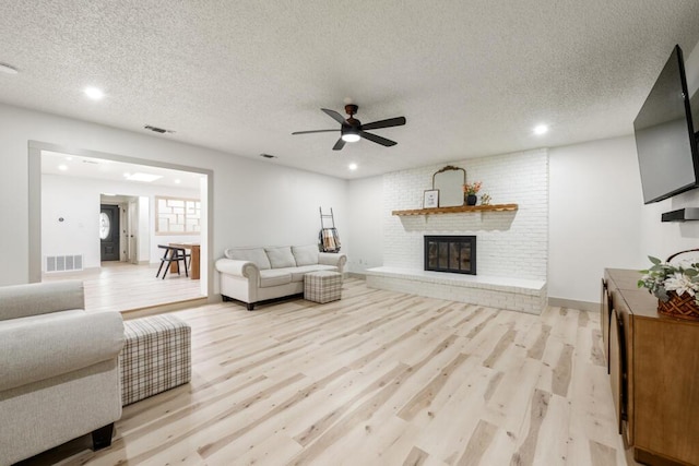 538 22nd St, Niceville, FL 32578 - living area with light wood-type flooring, a textured ceiling, a ceiling fan, a fireplace, and recessed lighting