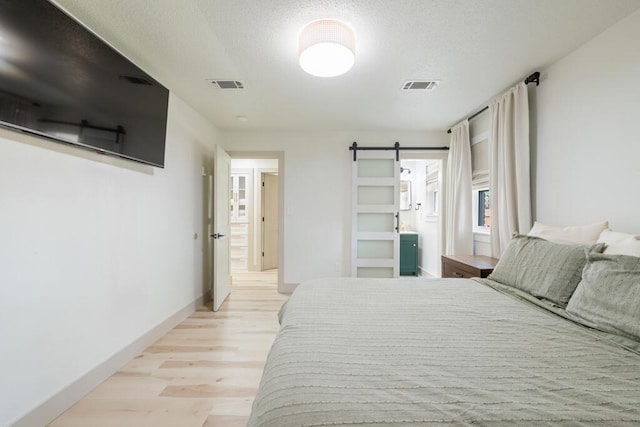 538 22nd St, Niceville, FL 32578 - bedroom with light wood-style flooring, a barn door, a textured ceiling, and baseboards