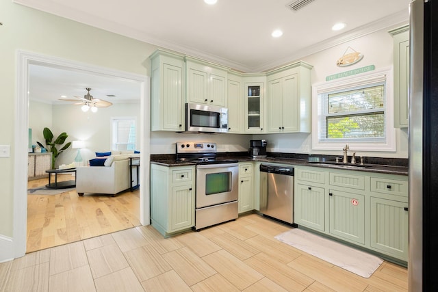 104 Derondo St, Panama City Beach, FL 32413 - kitchen with stainless steel appliances, a sink, green cabinetry, crown molding, and dark countertops