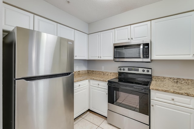 4270 Calinda Ln Unit 343, Niceville, FL 32578 - kitchen with appliances with stainless steel finishes, white cabinetry, light tile patterned flooring, a textured ceiling, and light stone counters