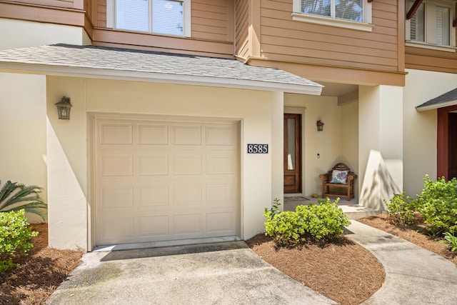 8585 Magnolia Bay Ln, Miramar Beach, FL 32550 - property entrance with a garage, stucco siding, driveway, and roof with shingles