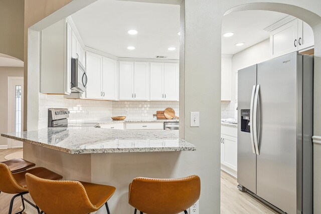 865 Indigo Loop, Destin, FL 32550 - kitchen featuring appliances with stainless steel finishes, arched walkways, a peninsula, backsplash, and white cabinets