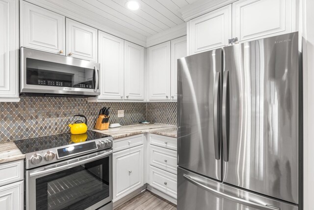 5209 Beachwalk Dr, Miramar Beach, FL 32550 - kitchen featuring appliances with stainless steel finishes, white cabinetry, backsplash, light stone counters, and light wood-style floors