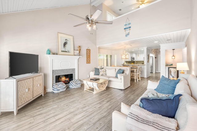 5209 Beachwalk Dr, Miramar Beach, FL 32550 - living room featuring ceiling fan, light wood-style floors, a tile fireplace, and high vaulted ceiling