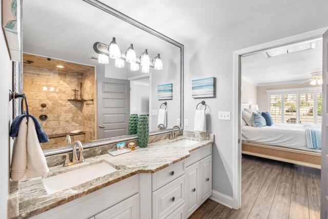 5209 Beachwalk Dr, Miramar Beach, FL 32550 - ensuite bathroom with double vanity, baseboards, crown molding, wood finished floors, and tiled shower