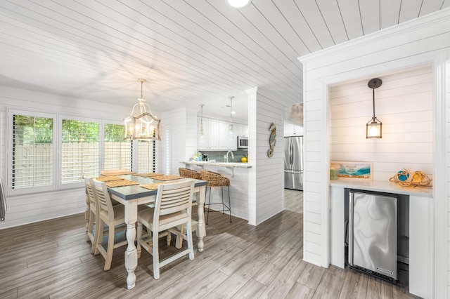 5209 Beachwalk Dr, Miramar Beach, FL 32550 - dining space with a chandelier, light wood finished floors, and wood walls