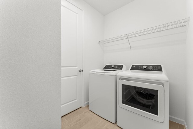8454 Dreams Float Ct, Panama City Beach, FL 32413 - laundry area featuring washing machine and clothes dryer, light wood-style floors, and baseboards