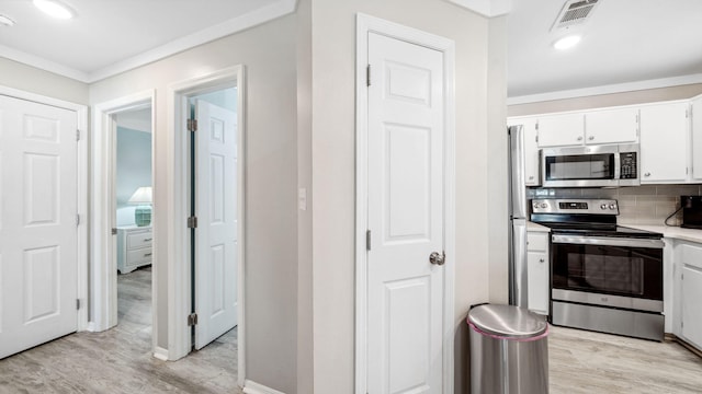 11 Beachside Dr Unit 722, Santa Rosa Beach, FL 32459 - kitchen with stainless steel appliances, light wood finished floors, white cabinetry, crown molding, and light countertops