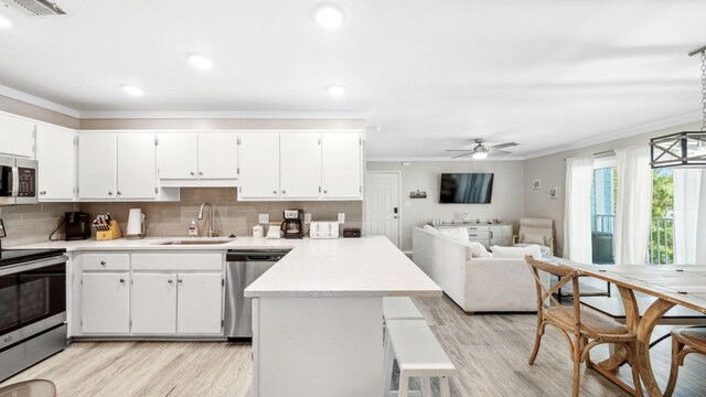 11 Beachside Dr Unit 722, Santa Rosa Beach, FL 32459 - kitchen with stainless steel appliances, a peninsula, crown molding, light wood finished floors, and light countertops