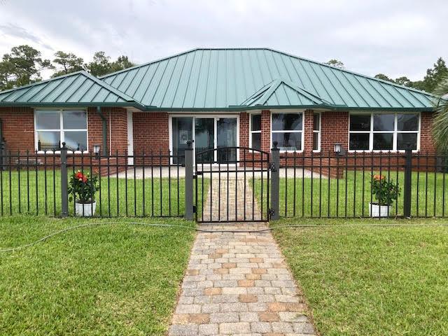 6735 Tidewater Dr, Navarre, FL 32566 - view of front of property with a standing seam roof, brick siding, metal roof, and a gate