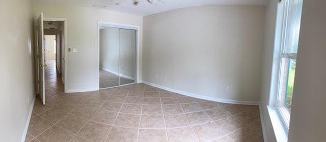 6735 Tidewater Dr, Navarre, FL 32566 - unfurnished bedroom with a closet, light tile patterned floors, and baseboards