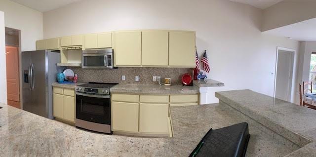 6735 Tidewater Dr, Navarre, FL 32566 - kitchen with appliances with stainless steel finishes, cream cabinets, decorative backsplash, and light stone counters
