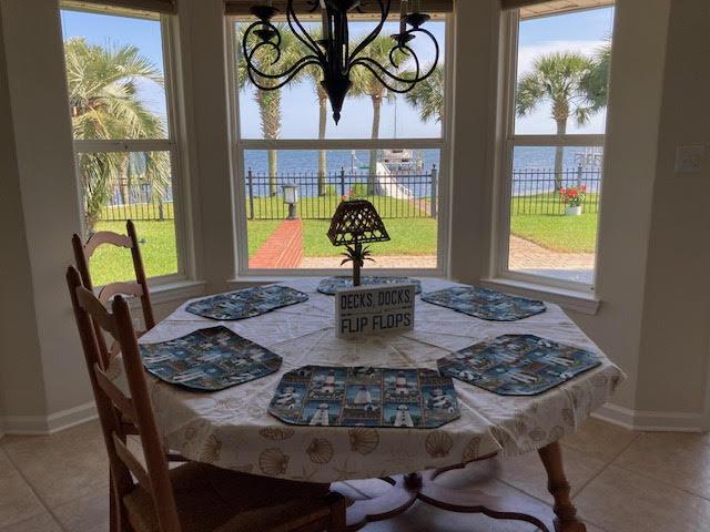 6735 Tidewater Dr, Navarre, FL 32566 - tiled dining room featuring a chandelier, plenty of natural light, and baseboards