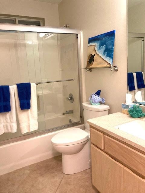 6735 Tidewater Dr, Navarre, FL 32566 - bathroom with vanity, enclosed tub / shower combo, toilet, and tile patterned floors