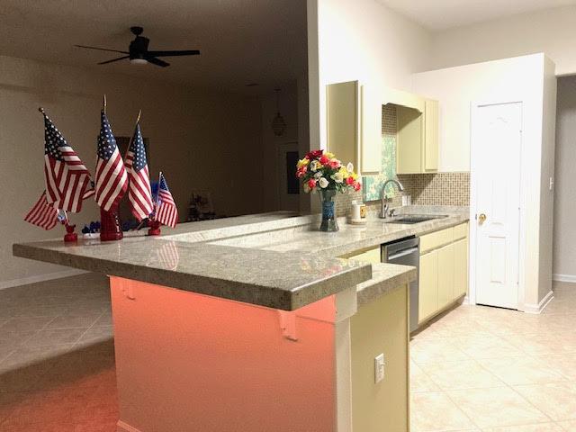 6735 Tidewater Dr, Navarre, FL 32566 - kitchen with a sink, dishwasher, a kitchen breakfast bar, a peninsula, and light tile patterned flooring